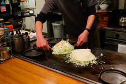 Okonomiyaki Hier sieht man jemanden beim Live Cooking.