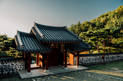 Ein Tempel vor grünen Baumwipfeln, die von der untergehenden Sonne angestrahlt werden. 