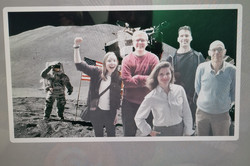 A group of people seems to be on the moon. In the background, you can see an astronaut and a US flag.