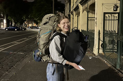 Abschied Melbourne Hier sieht man Lilly, die lacht, und hinten und vorne einen Rucksack trägt.