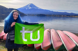 Flagge Hier sieht man die Studentin am Wasser, wie sie die TU Flagge hochhält.