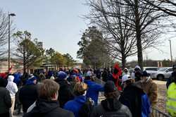 Viele Studierende in blauen Jacken und Mützen laufen auf der Straße im Winter. 