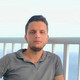 Testimonial Hassoun A portrait of a young man. A railing and the sea can be seen in the background.