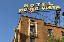 Hotel Monte Vista in Flagstaff Hier sieht man ein rotes Backsteinhaus, auf dem in großen gelben Buchstaben "Hotel Monte Vista" geschrieben steht.