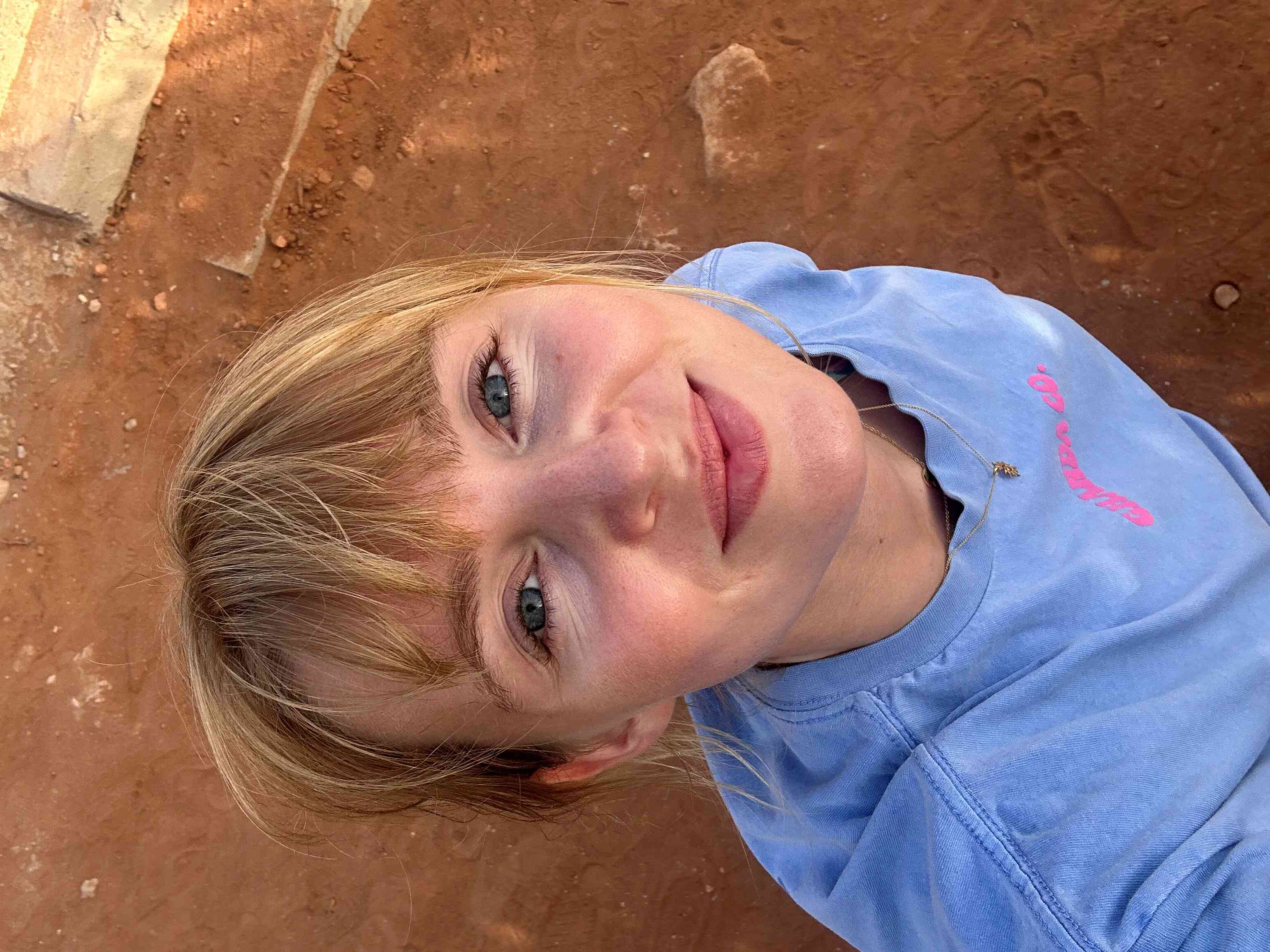 Junge Frau mit blauem Oberteil macht ein Selfie von oben