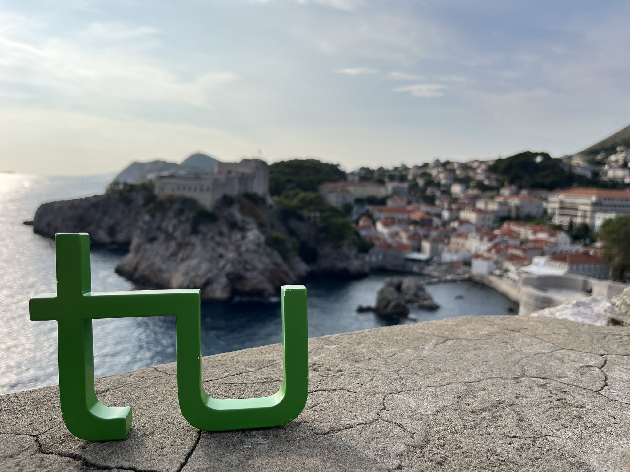 Foto des TU Logos mit Sicht auf eine Stadt