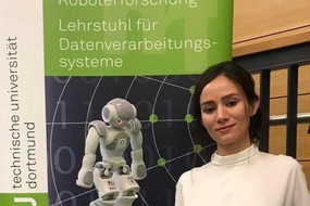 Eine junge Frau vor einem TU Dortmund-Plakat 