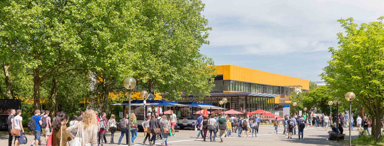 Students on the North Campus with the main cafeteria in the background in summer 