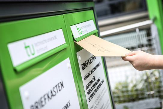 Eine Hand wirft einen Umschlag in den Fristenbriefkasten