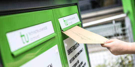 Eine Hand wirft einen Umschlag in den Fristenbriefkasten