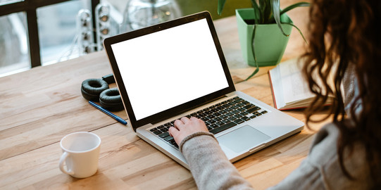 over-the-shoulder-Aufnahme einer Person, die am Laptop sitzt